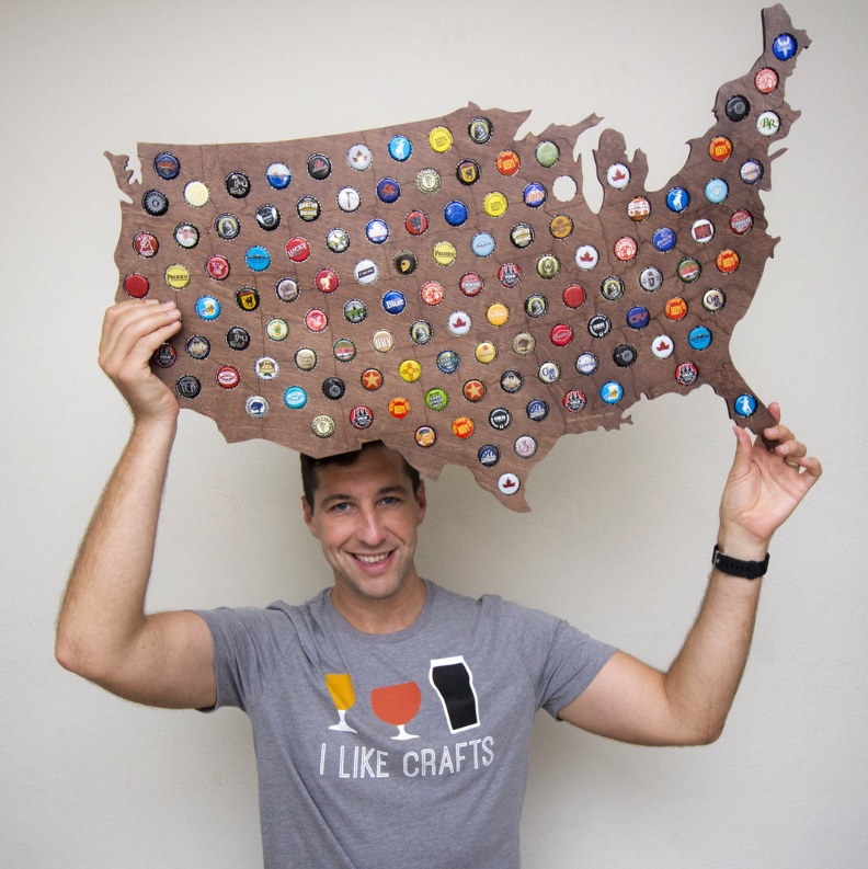 Andrew Erickson holding his first product, a wooden US map beer cap display